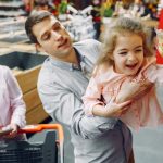 Joyful family of three enjoying grocery shopping together in a supermarket.